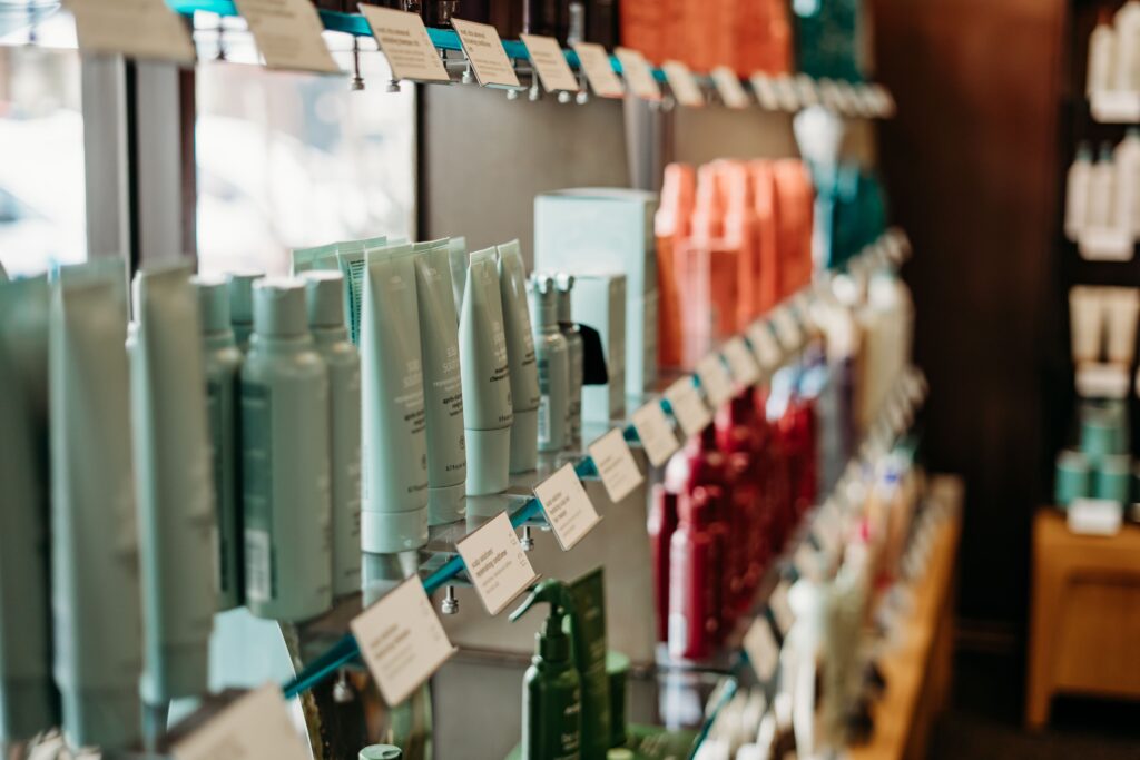 Salon Indigo in Fraser, MI Shelves stocked with various hair products and skin care essentials, all organized by color, with product labels and price tags visible. Salon Indigo in Fraser, MI
