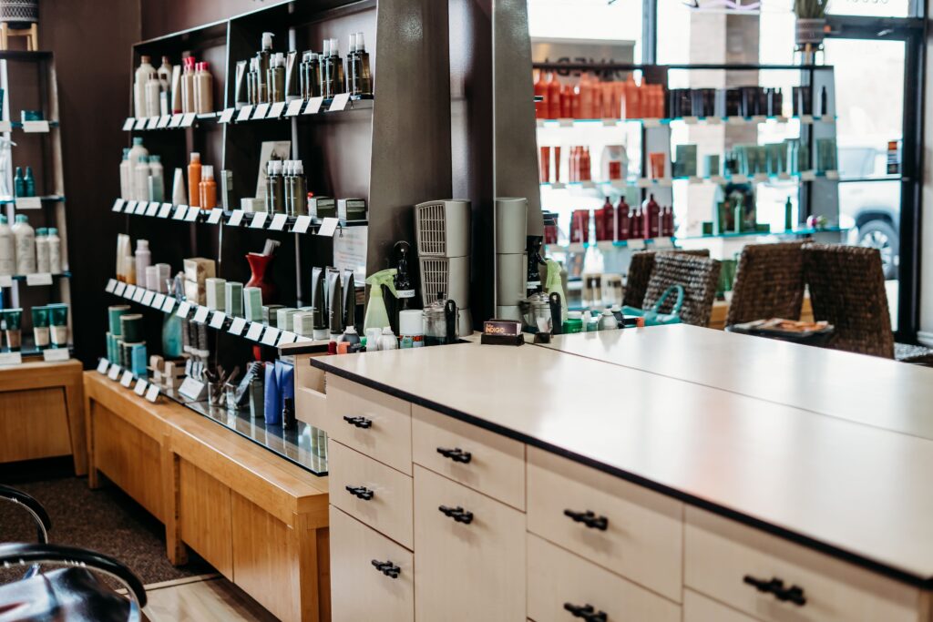 Salon Indigo in Fraser, MI Shelves in a salon display various hair care and skin care products, with a counter and drawers in the foreground—perfect for any hair stylist’s needs. Salon Indigo in Fraser, MI